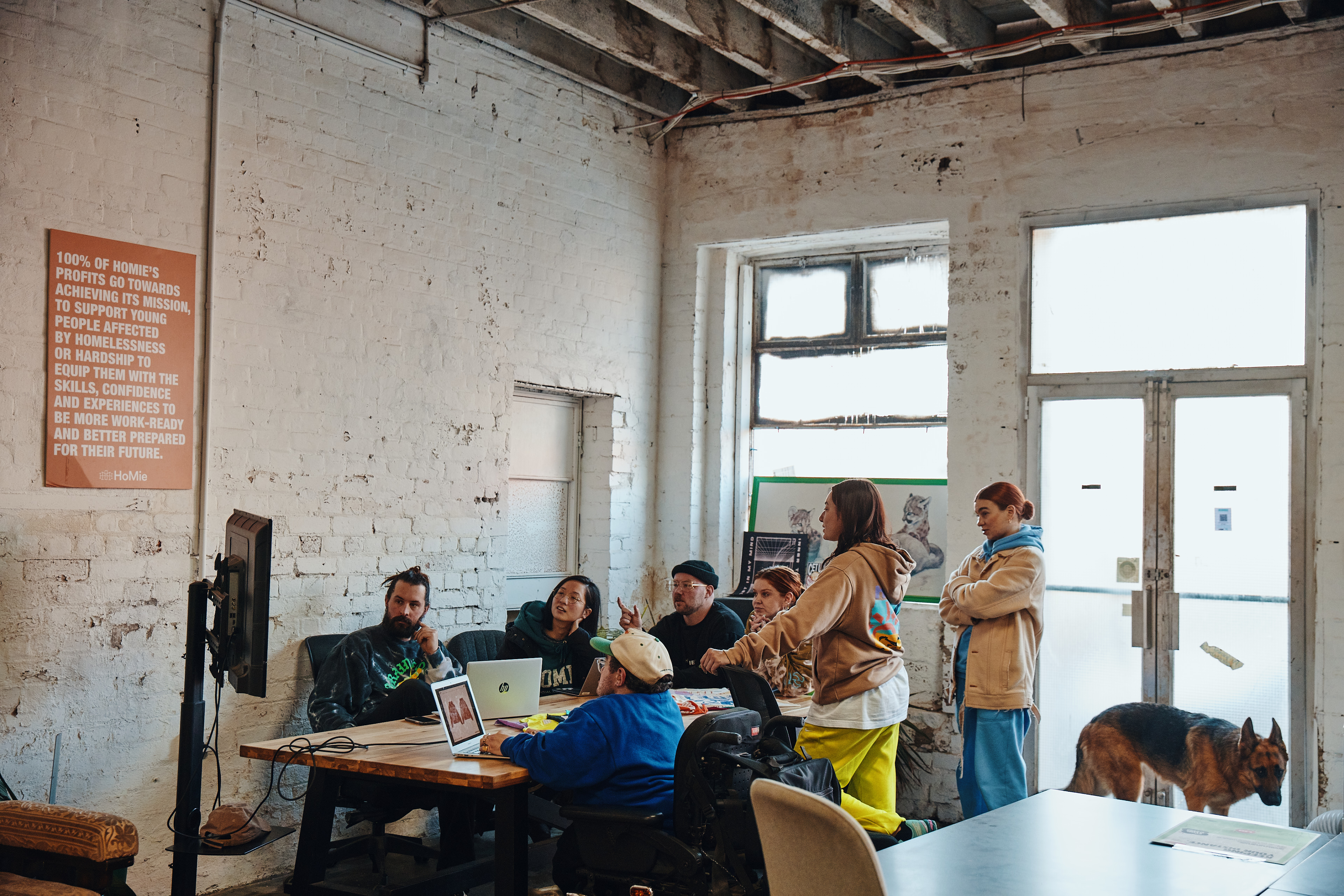 Group of people gathered around in an industrial style room at a table