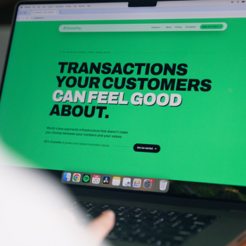 Laptop screen displaying a green GreenPay website with the bold headline "Transactions your customers can feel good about."